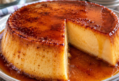 Flan de leche condensada desmoldado sobre plato blanco, con caramelo dorado fluyendo por los lados