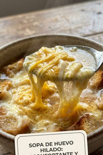 Tazón de sopa de huevo hilado con caldo dorado y hilos de huevo cocido flotando en la superficie, servida con cebollín verde picado